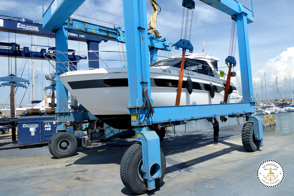 Motor yacht supported in the slings of a blue travel lift